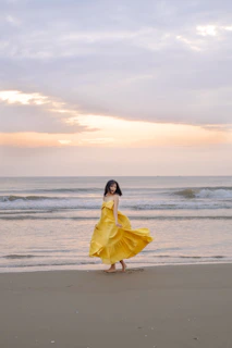 Flowing maxi dress caught in a gentle ocean breeze on a sandy beach at sunset