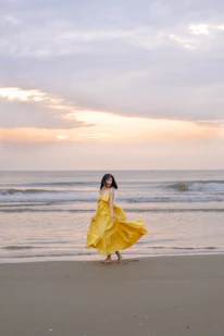 Flowing maxi dress caught in a gentle ocean breeze on a sandy beach at sunset