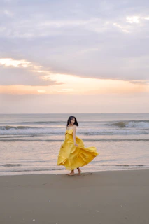 Flowing maxi dress caught in a gentle ocean breeze on a sandy beach at sunset