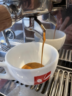 Close-up of a barista carefully pouring espresso into a classic white cup.