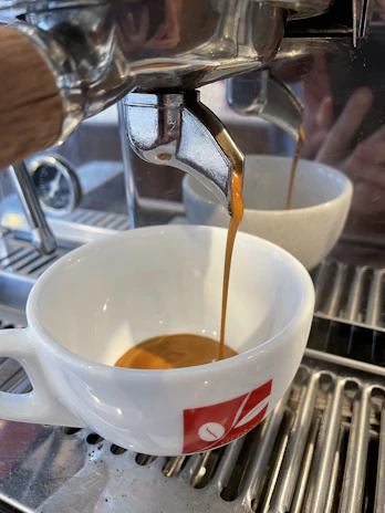 Close-up of a coffee machine pouring rich espresso into a white ceramic cup