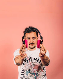 a man wearing headphones and holding up two pink mp3 players
