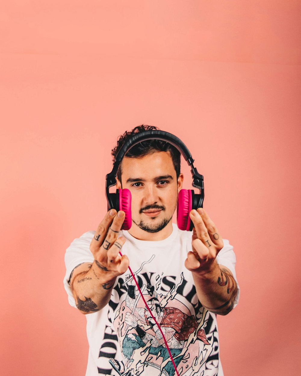 a man wearing headphones and holding up two pink mp3 players