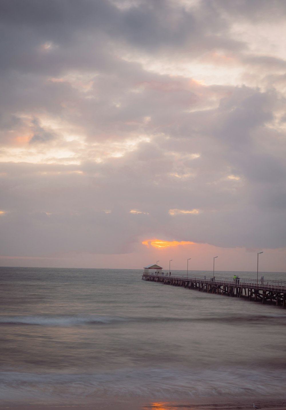 a pier with a boat in the distance on a cloudy day