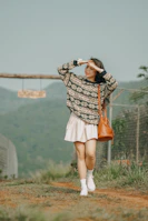 A casual scene of a student carrying a sage green cwtch bag while walking on a sunlit campus path.