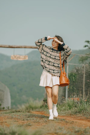 A casual scene of a student carrying a sage green cwtch bag while walking on a sunlit campus path.