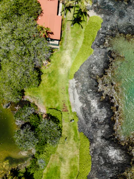 A sweeping aerial shot of Antigua's turquoise waters and lush green hills at sunset.