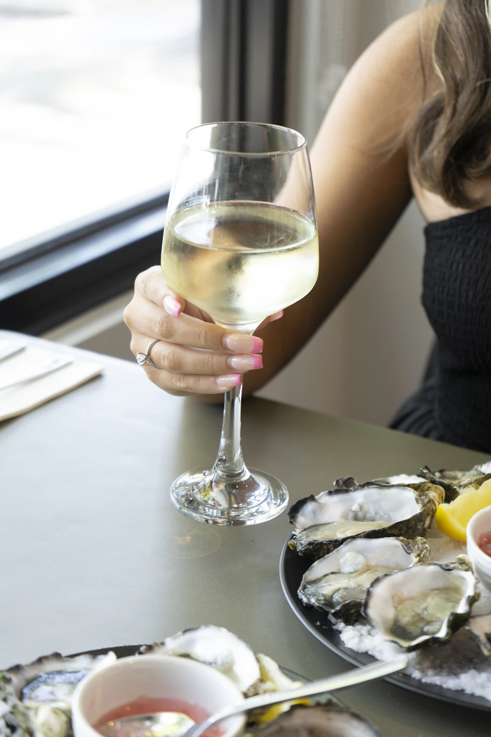 A woman sitting at a table with a glass of wine
