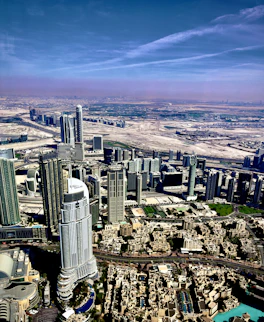 Aerial view of a futuristic modular city rising from a vast desert landscape under a clear blue sky.