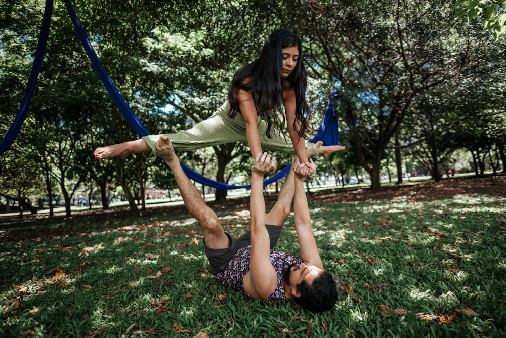 a man and a woman doing a handstand in a park