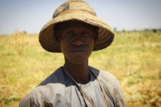 a man in a straw hat standing in a field