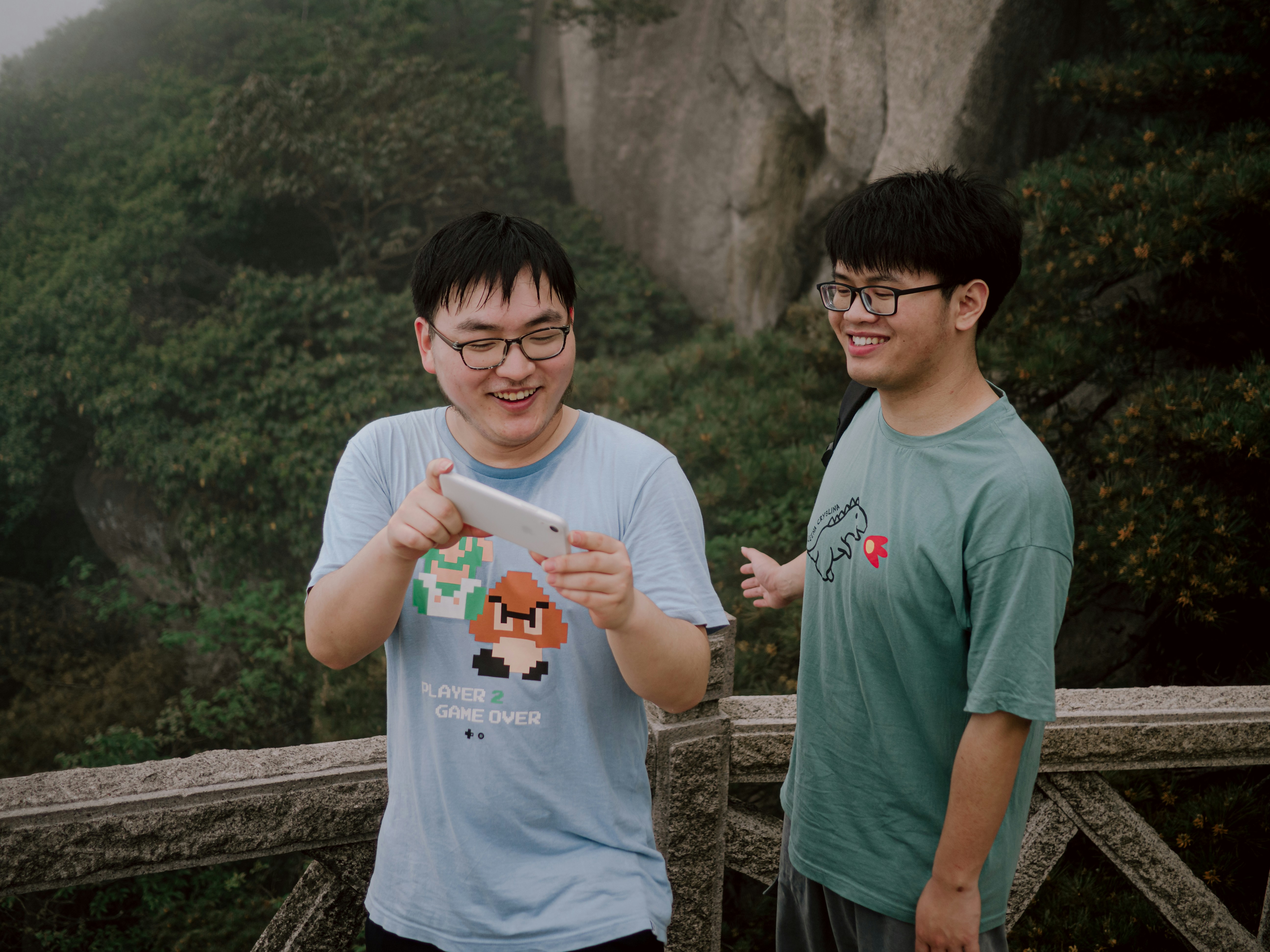two young men standing next to each other on a bridge