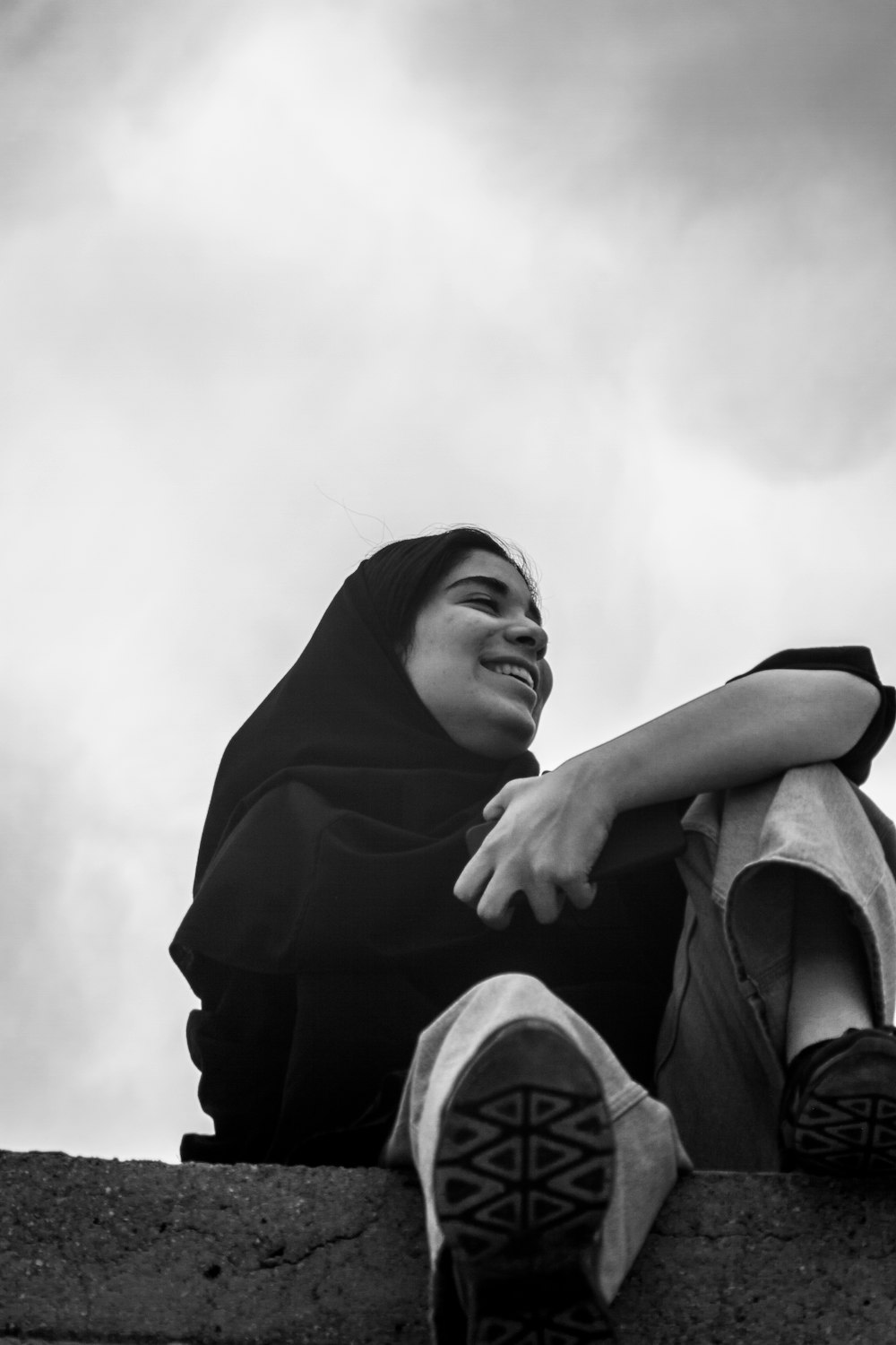 a woman sitting on top of a cement wall