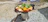 Photo of a compact foldable grill set up on a small balcony with fresh vegetables grilling.