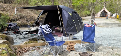 A large, rugged cooler with ice and beverages beside a camping tent.