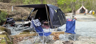 A large, rugged cooler with ice and beverages beside a camping tent.