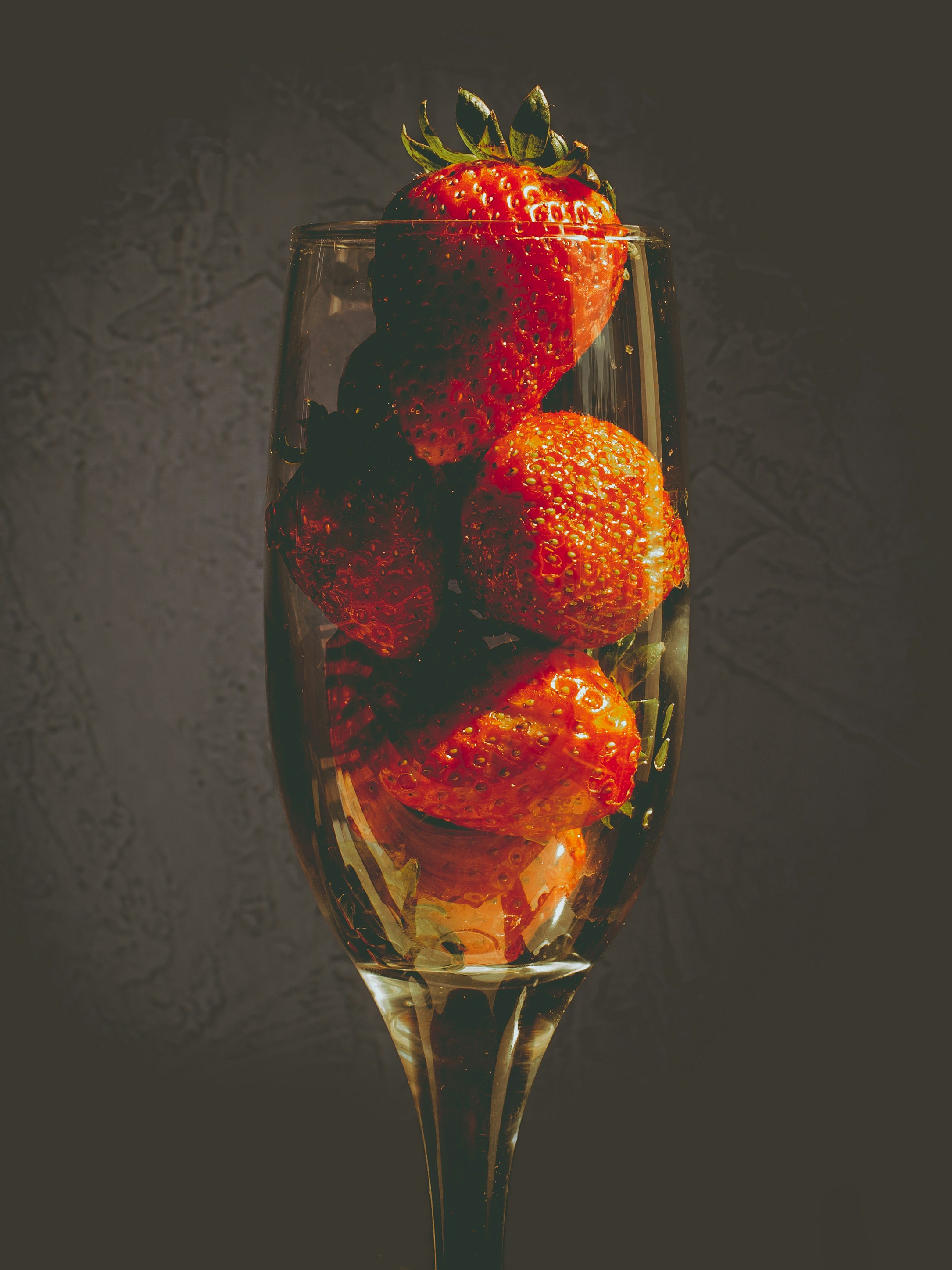 a glass of water with strawberries in it