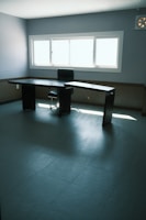 Home office space with a minimalist desk and ergonomic chair near a window.