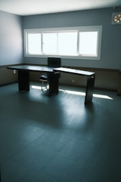 An elegant L-shaped office desk in a bright, airy room with minimal clutter