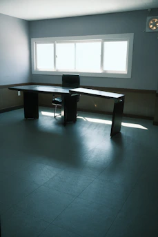 A serene office space with minimalist design, featuring a sleek desk, a laptop, and soft natural light filtering through blinds.