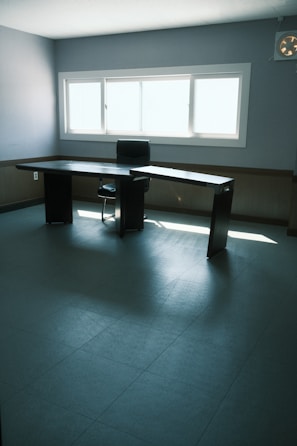 Home office space with a minimalist desk and ergonomic chair near a window.