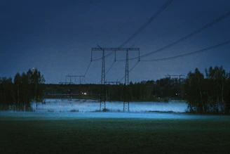 Powerlines stretching across a vast, calm landscape at dusk.
