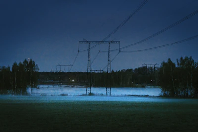 Powerlines stretching across a vast, calm landscape at dusk.
