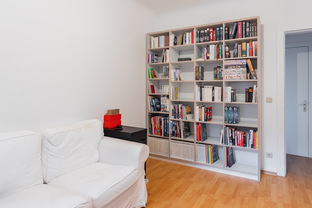 a white couch sitting in a living room next to a book shelf