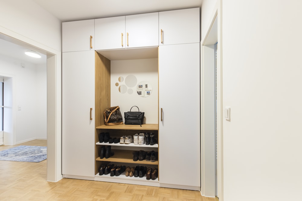 a white closet with a shoe rack and a handbag