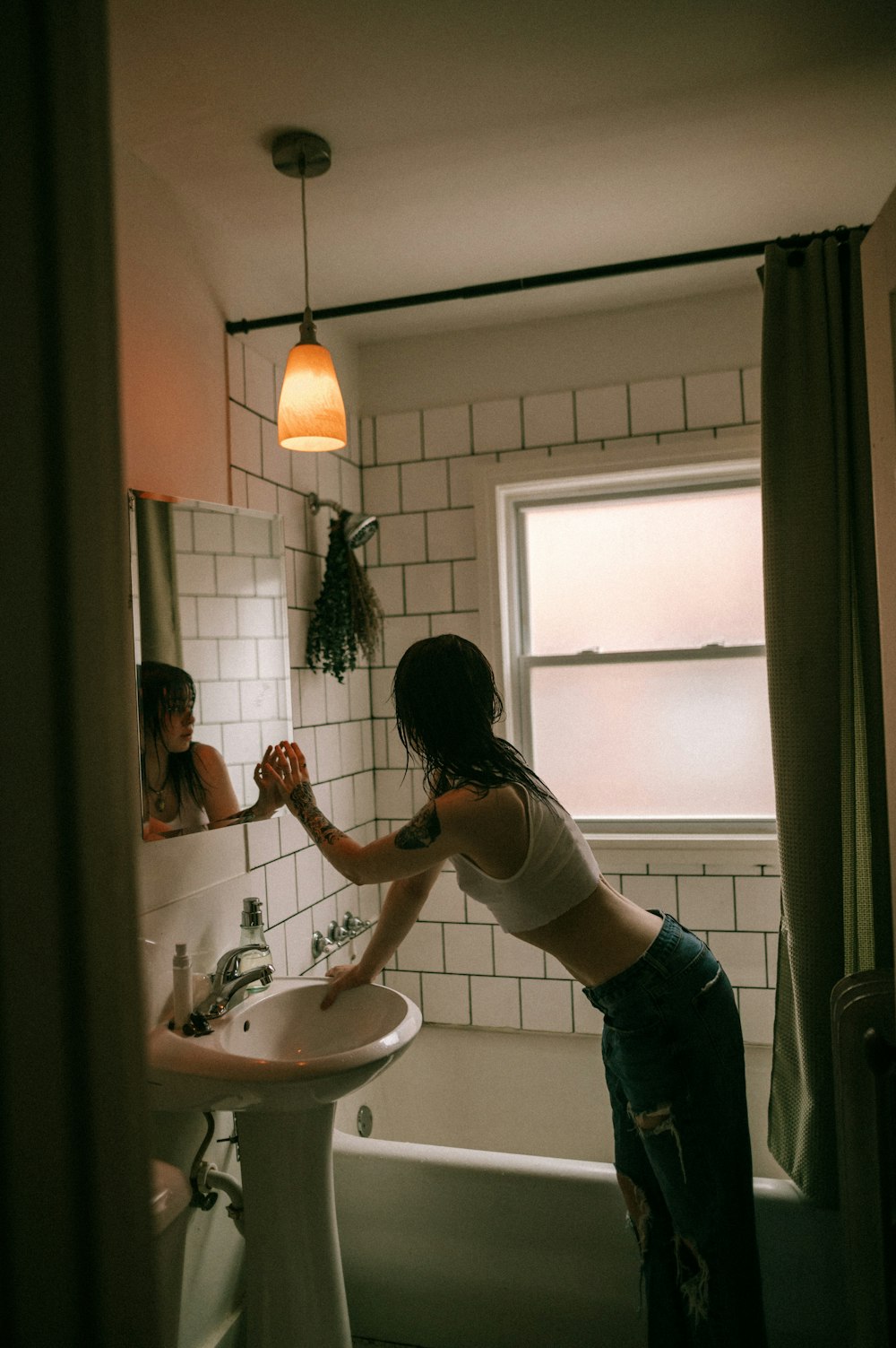 a woman standing in a bathroom next to a sink