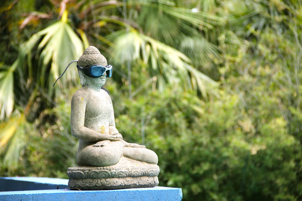 a statue of a buddha sitting on top of a blue wall