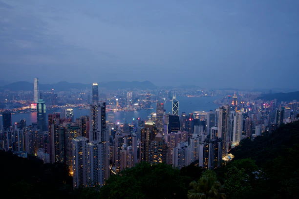 A panoramic view of Hong Kong’s skyline at dusk, with glowing city lights and towering skyscrapers.