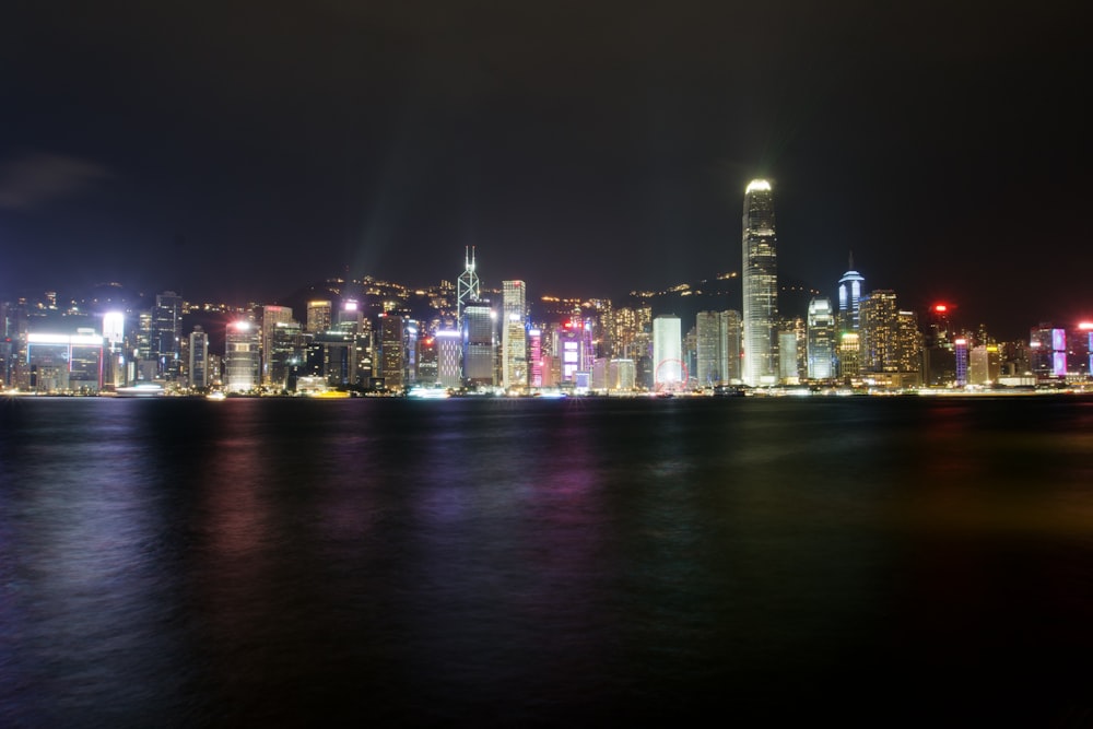 a city skyline at night with lights reflecting off the water