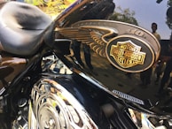 Close-up of a Harley Davidson motorcycle's chrome details shining under the afternoon sun during a club meetup.