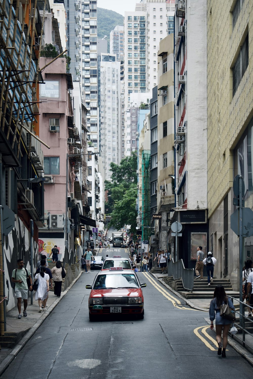 a red car driving down a street next to tall buildings