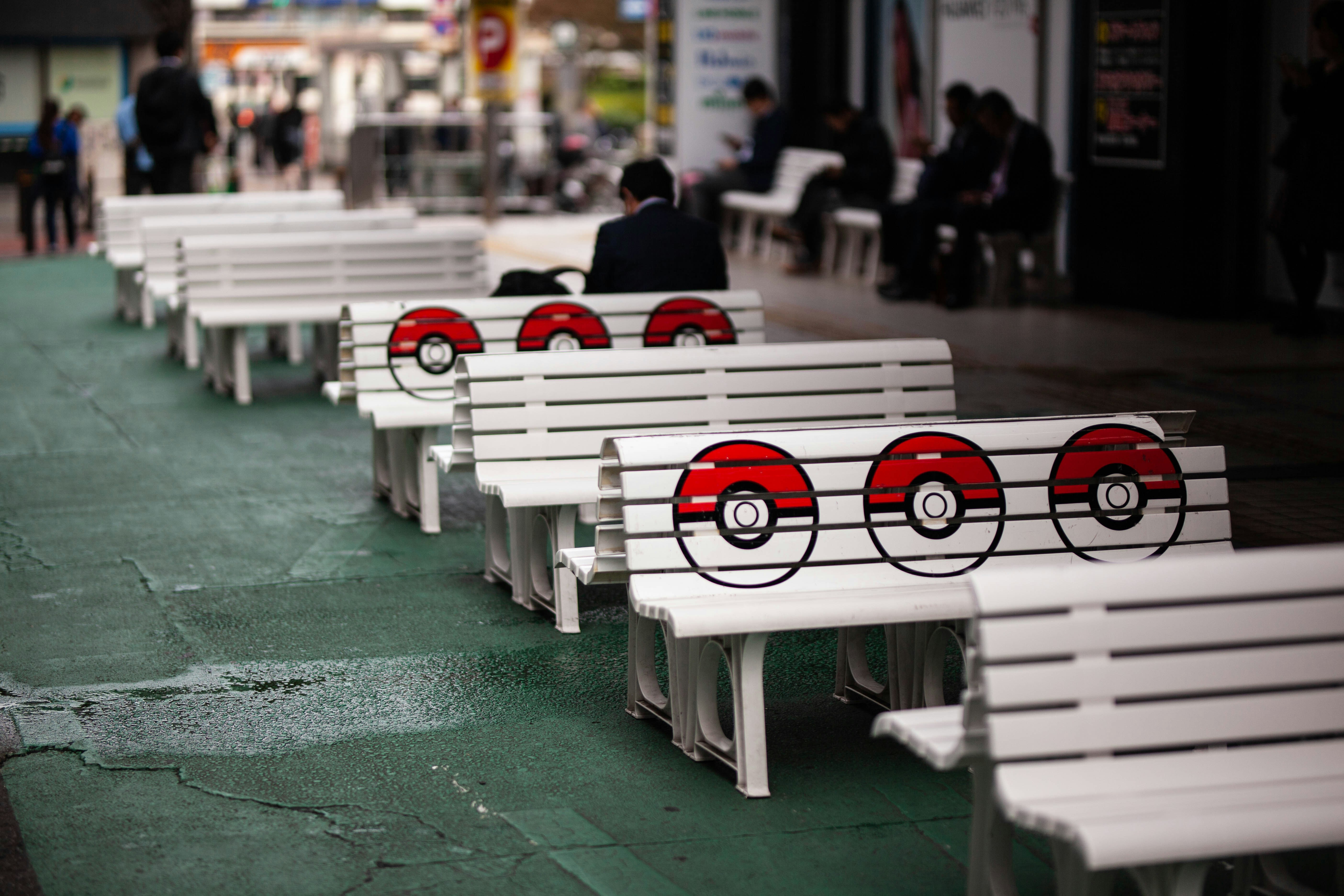 a row of white benches sitting on top of a sidewalk