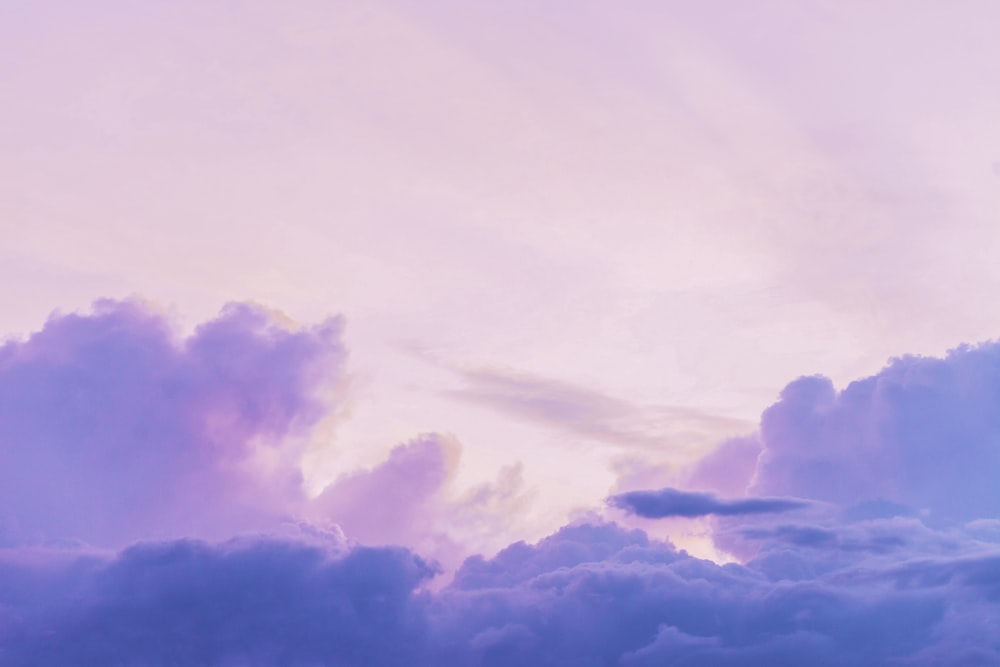 a plane flying through a cloudy blue sky