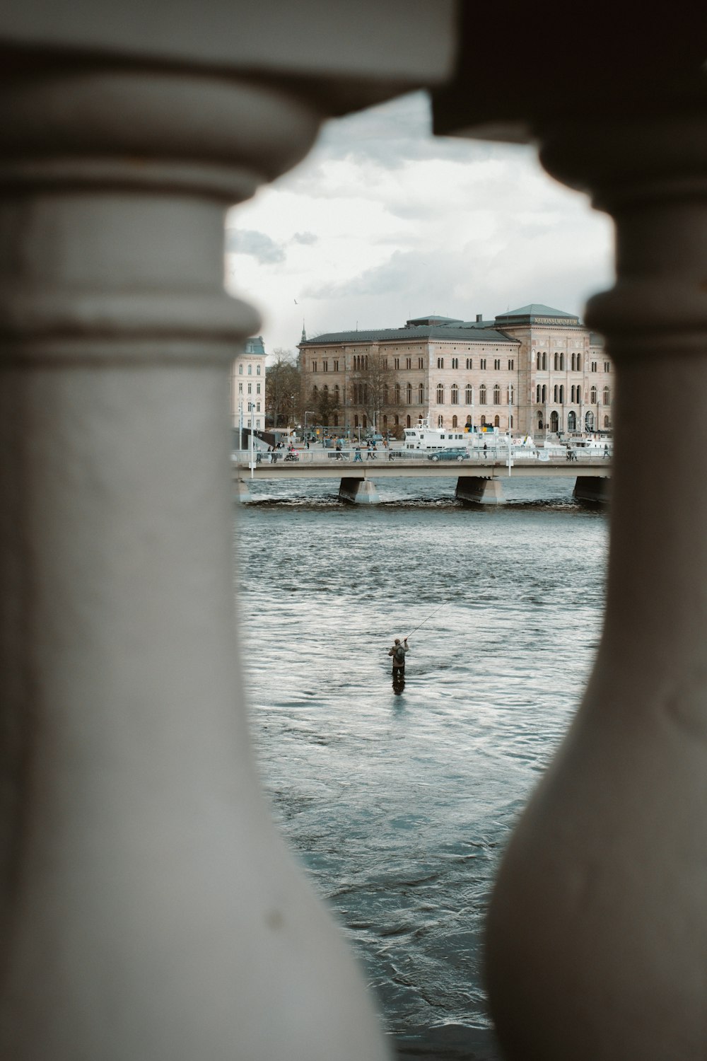 a man standing in a body of water next to a tall building