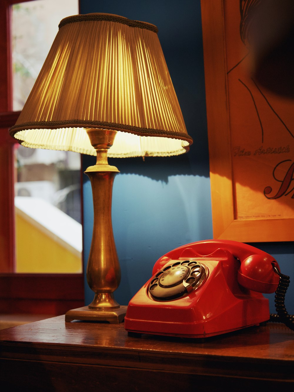 a red telephone sitting on top of a wooden table