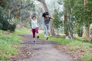 two women running down a path in the woods