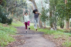 two women running down a path in the woods