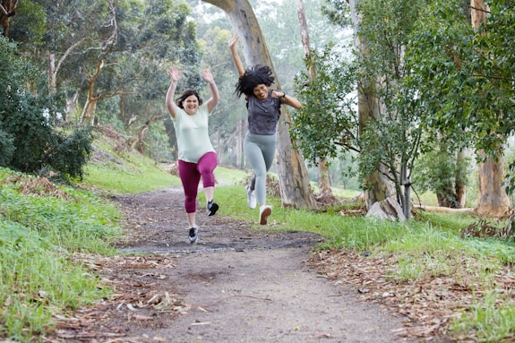 two women running down a path in the woods