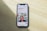 A smartphone displaying a website is placed on a wooden surface. The website features text in Polish and an image of two people standing together with indoor plants in the background.