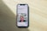 A smartphone displaying a website is placed on a wooden surface. The website features text in Polish and an image of two people standing together with indoor plants in the background.