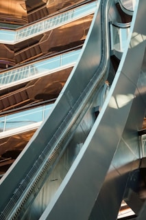 A modern architectural structure featuring reflective surfaces and geometric shapes. The composition includes sleek metallic materials and glass panels, creating a dynamic and futuristic appearance.