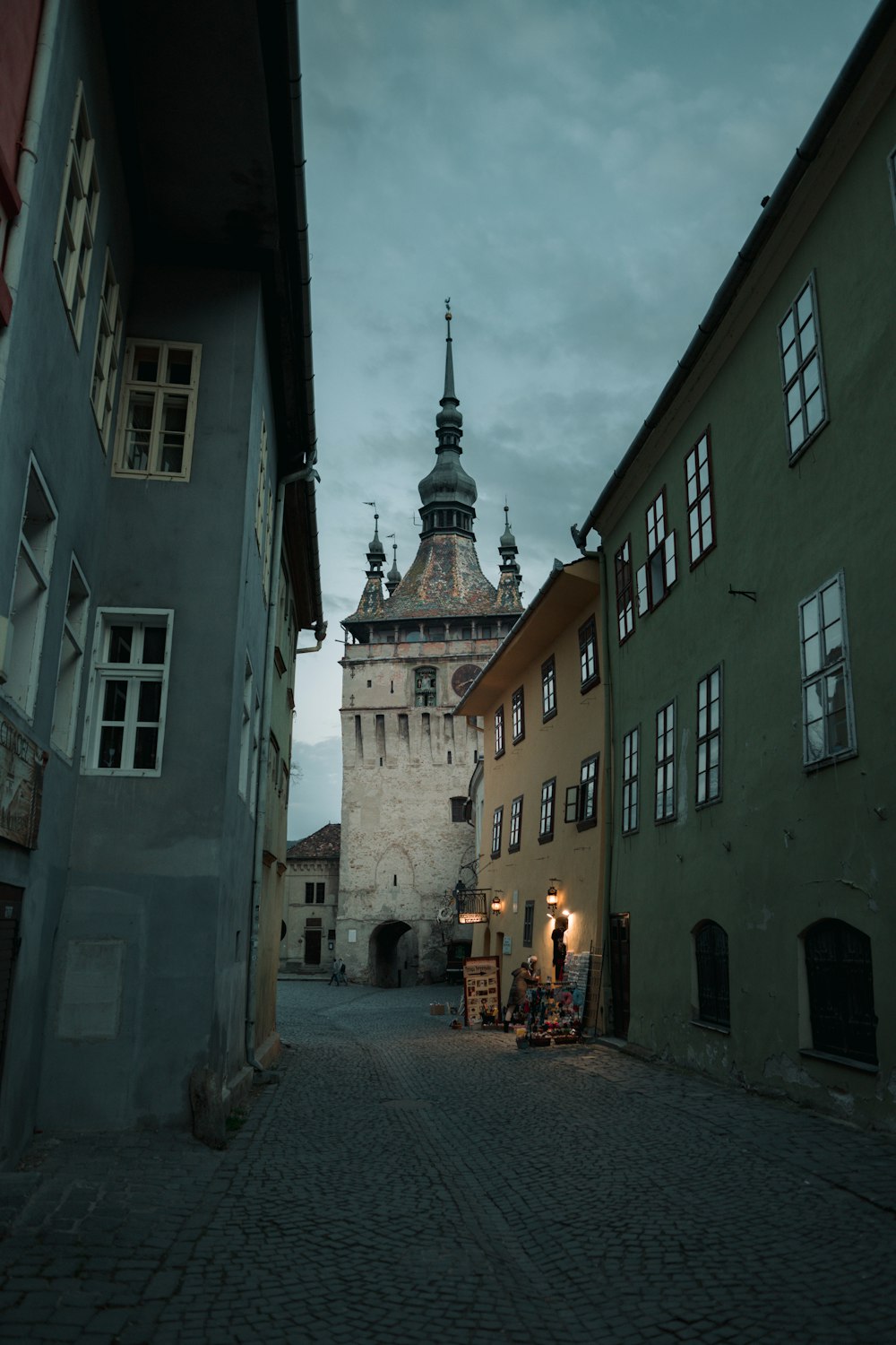 a cobblestone street with a clock tower in the background