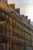 A row of classic European-style apartment buildings with ornate balconies and chimneys, bathed in warm light. The buildings have a historic architectural design, featuring large windows and intricate details.
