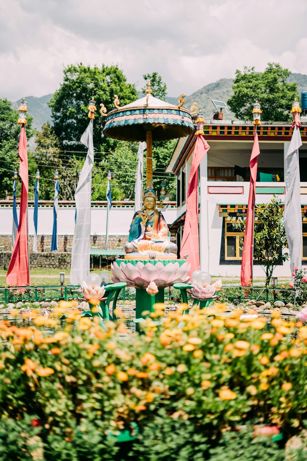 a small fountain surrounded by flags and flowers