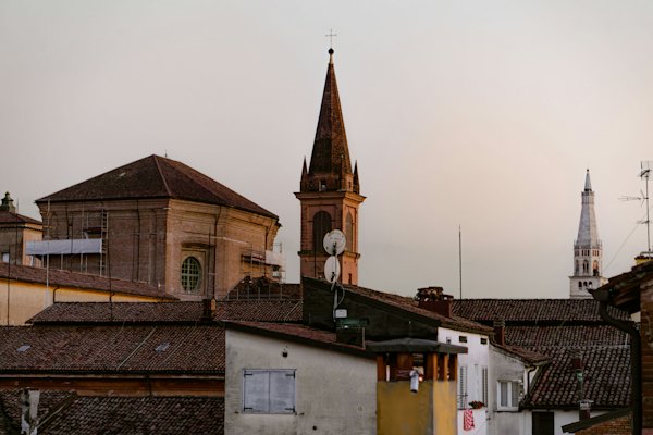 A church steeple rises above a row of buildings — Modena, Italy