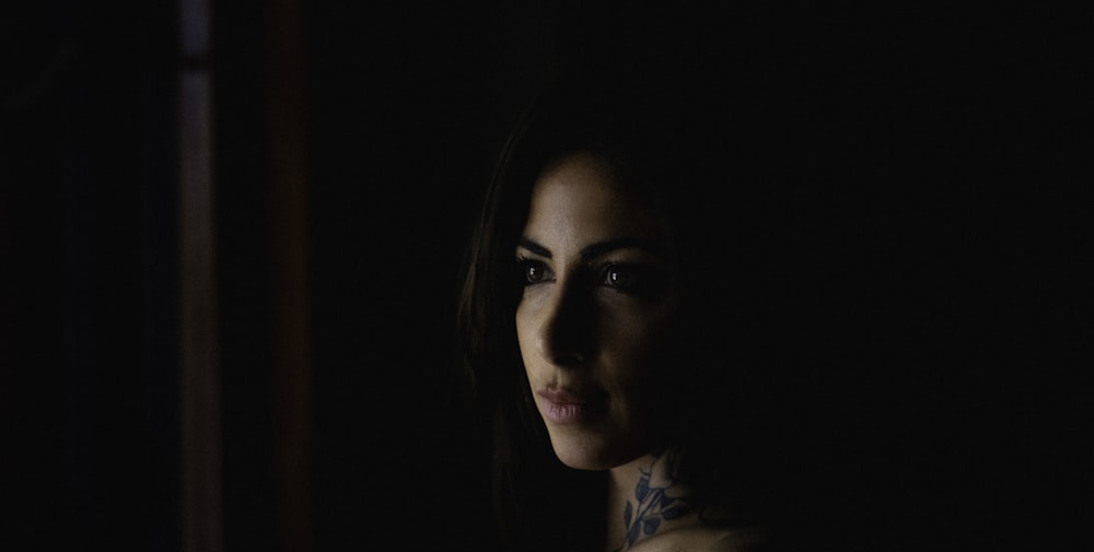 a woman with a tattoo on her chest in the dark